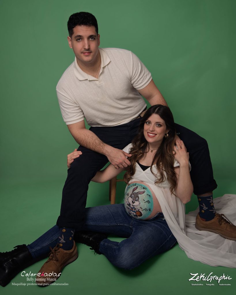 Mujer embarazada con dibujo pintado en la barriga y su marido sonriendo. Sesion de fotos en Murcia