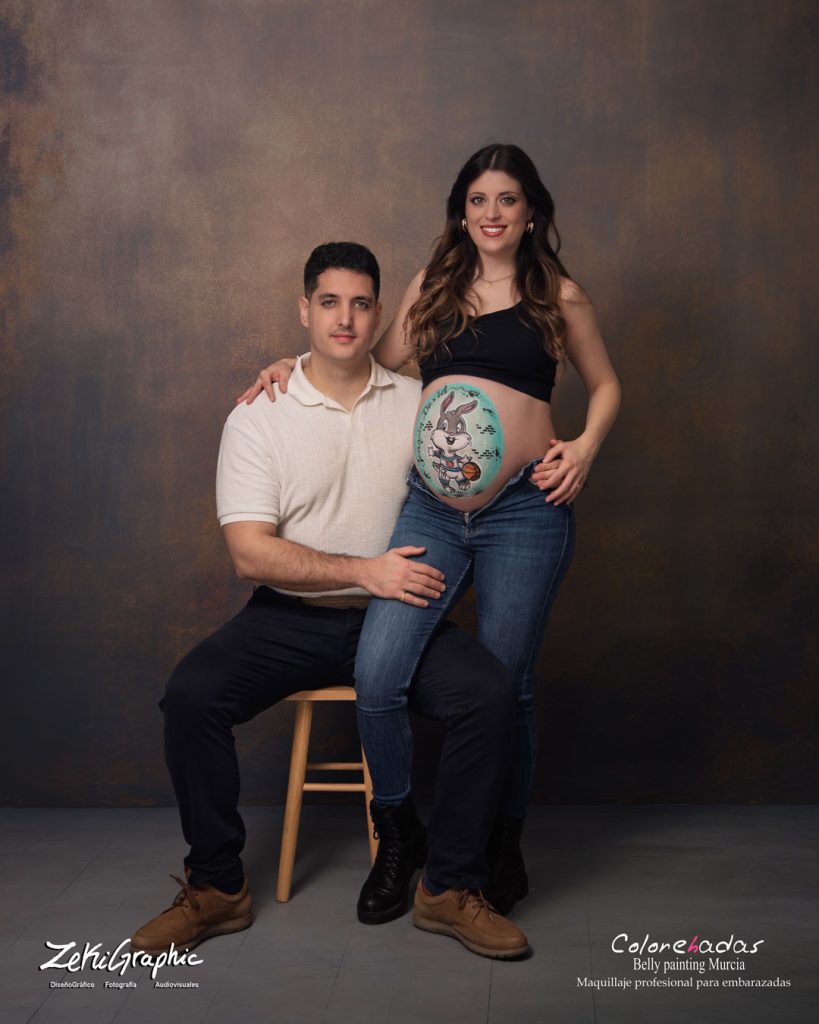 Mujer embarazada con dibujo pintado en la barriga y su marido sonriendo. Sesion de fotos en Murcia